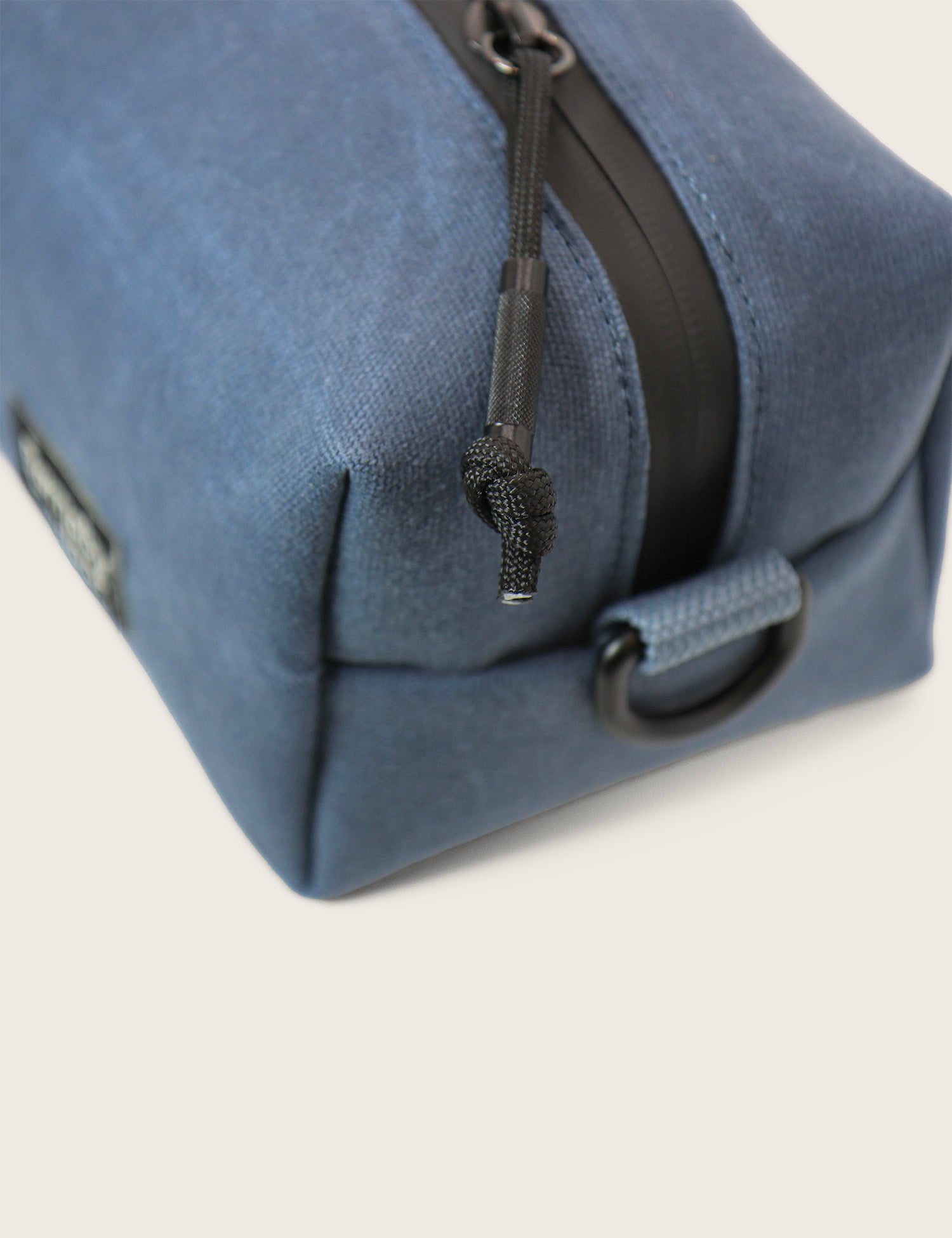Blue toiletry bag with a black zipper on a light gray background