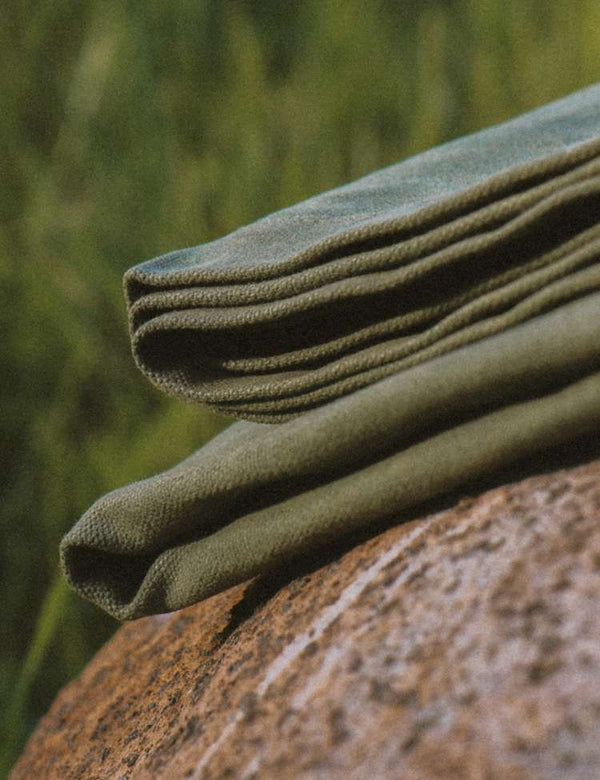 Folded green fabric on a textured rock with a blurred natural background