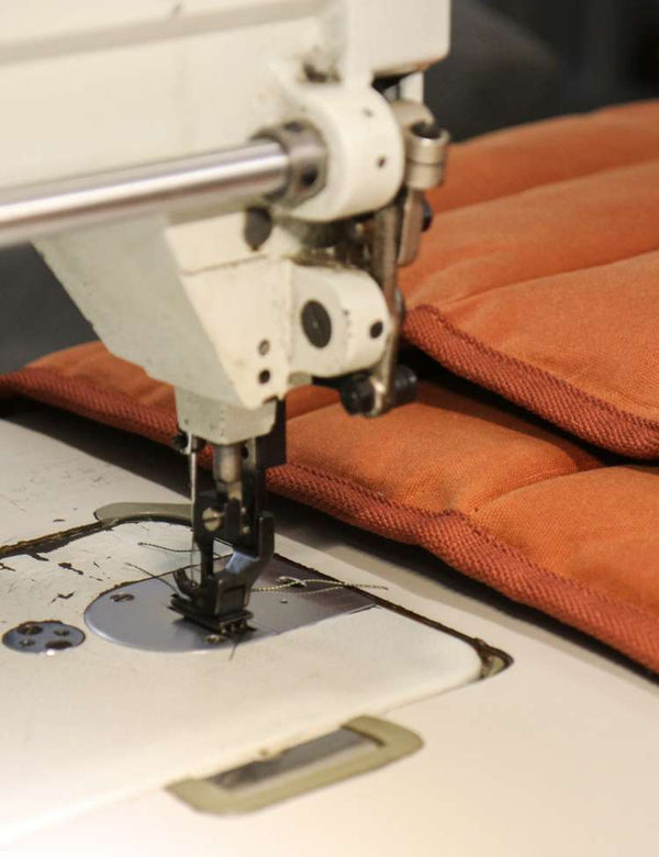 Sewing machine stitching orange fabric on a dark background