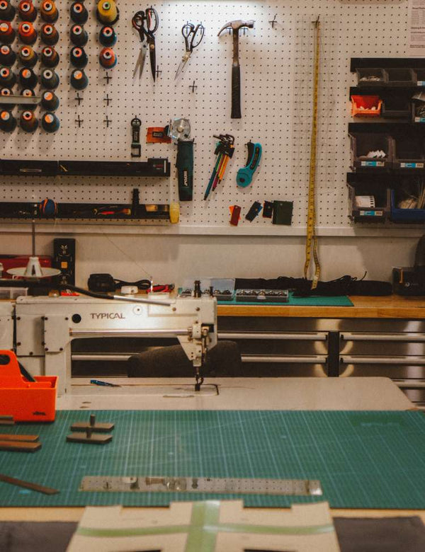 Workshop with sewing machine, tools on pegboard, and cutting mat.
