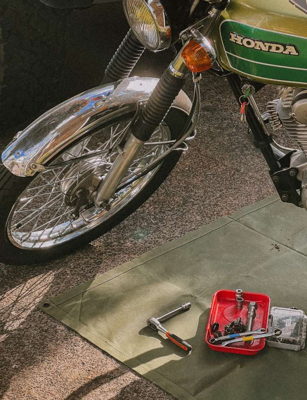 Honda motorcycle with tools on a green waxed canvas mat