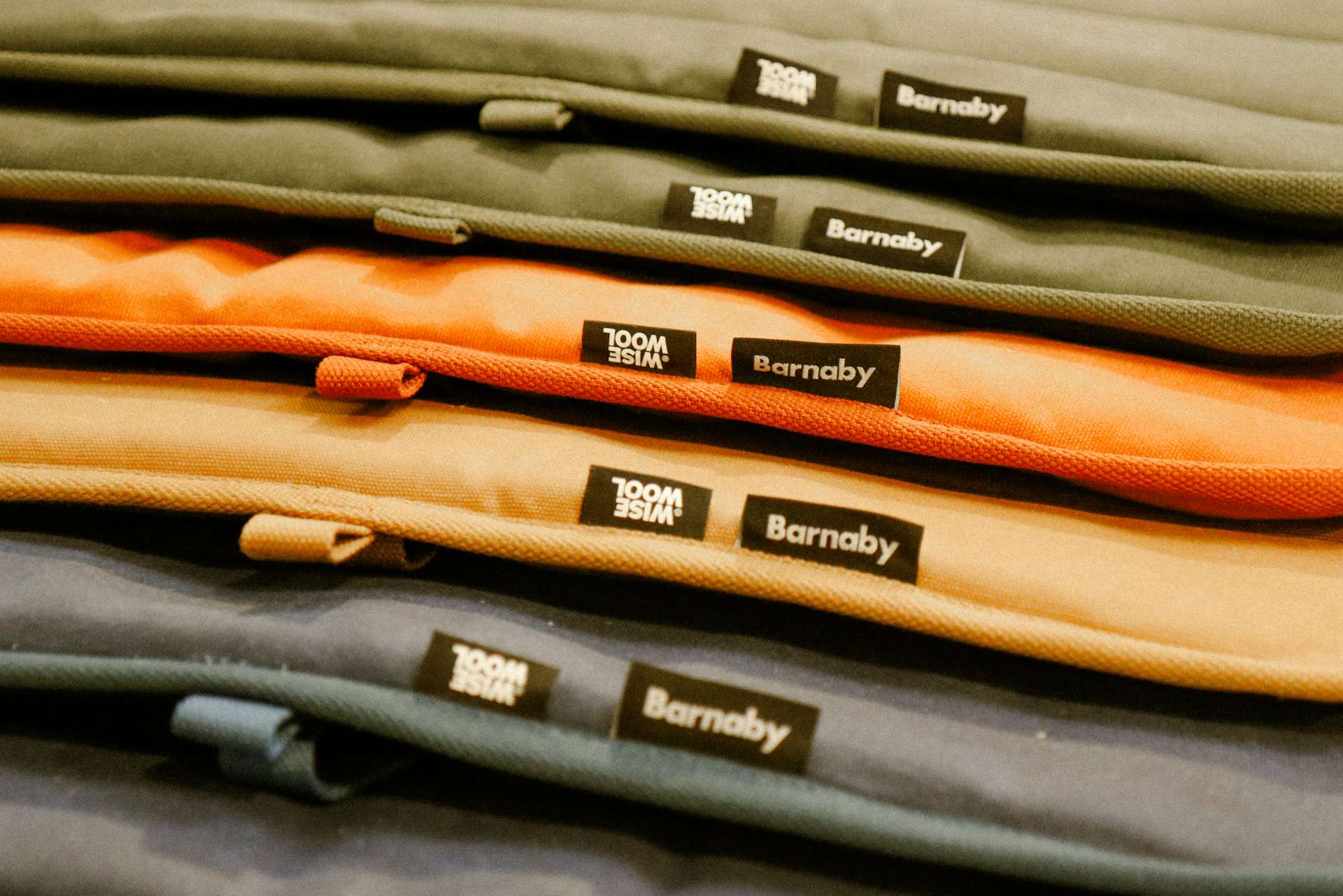 Stack of folded dog mats made form waxed canvas with Barnaby branding on labels