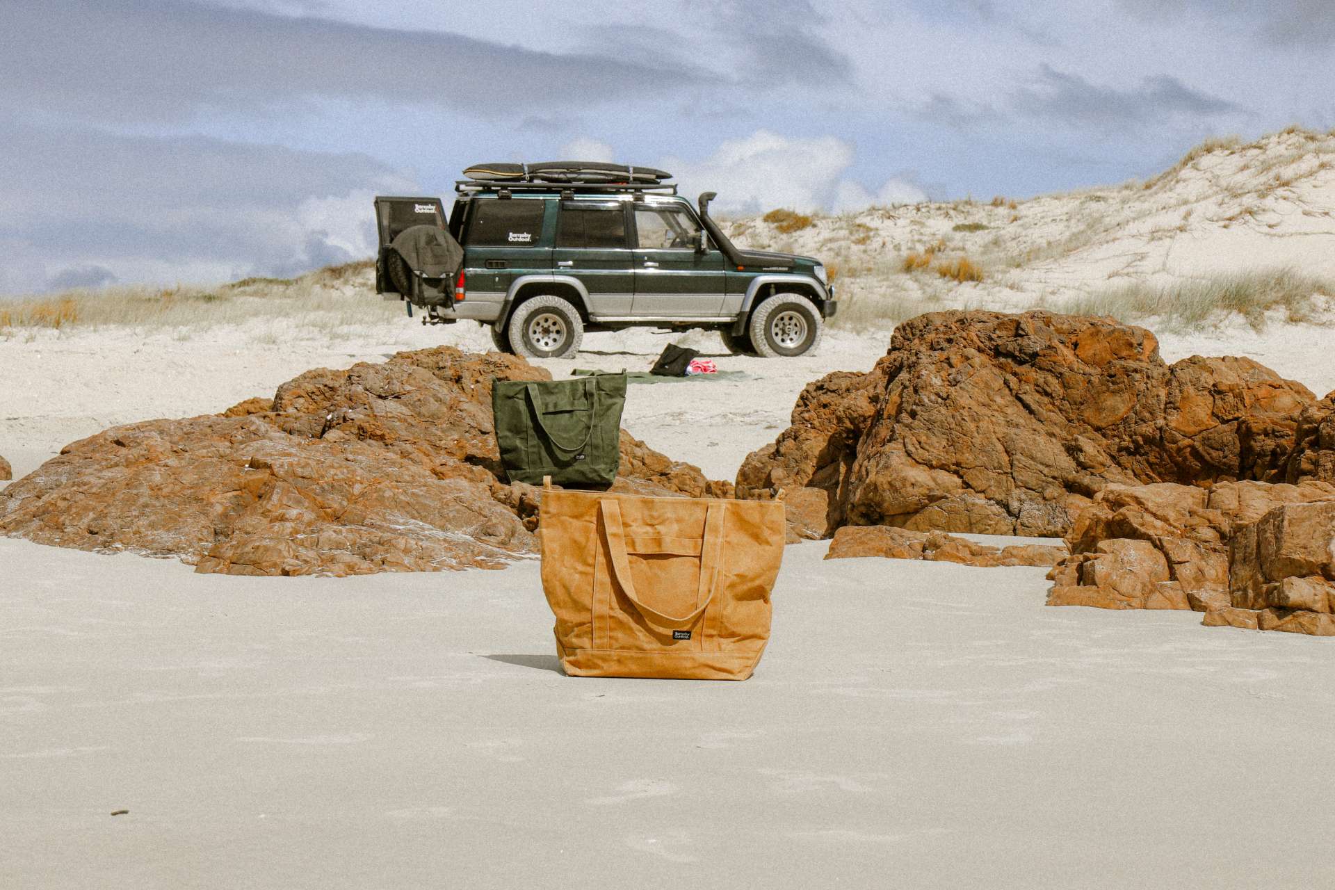Brown bag on sand with vehicle and landscape in background